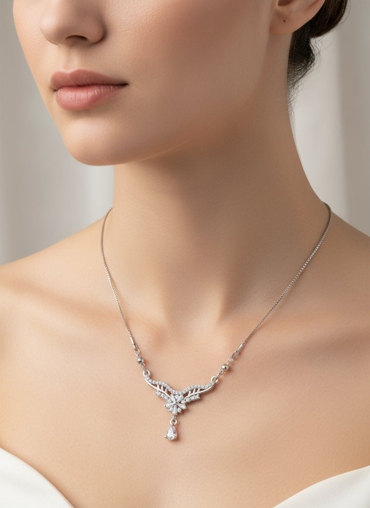 Close-up of a woman wearing a silver necklace with a pendant against a neutral background