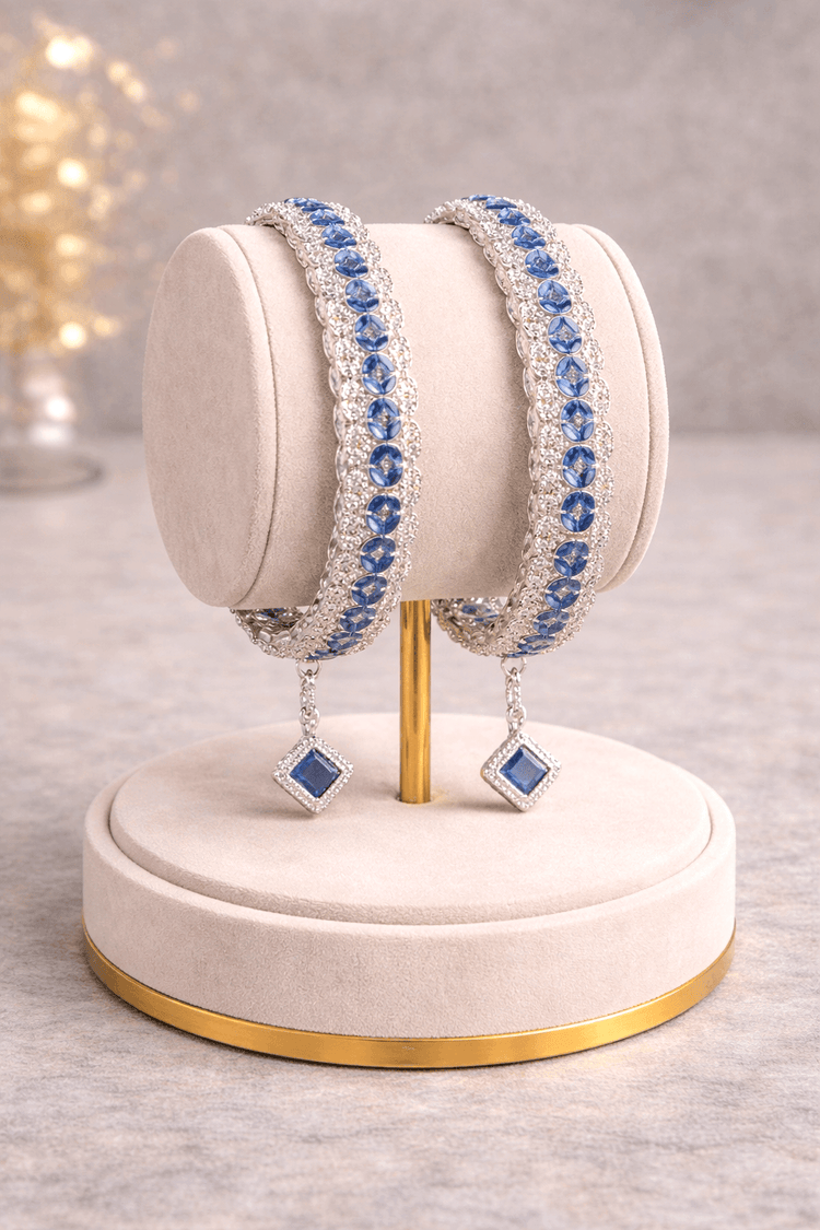 Two blue beaded bracelets on a white stand with a blurred background
