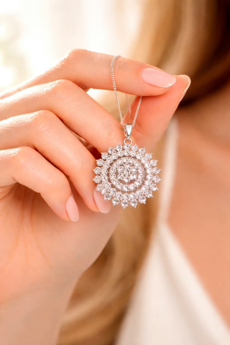 Close-up of a hand holding a diamond necklace with a spiral design.