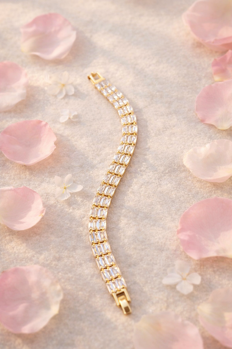 Gold bracelet with clear stones on a soft pink floral background