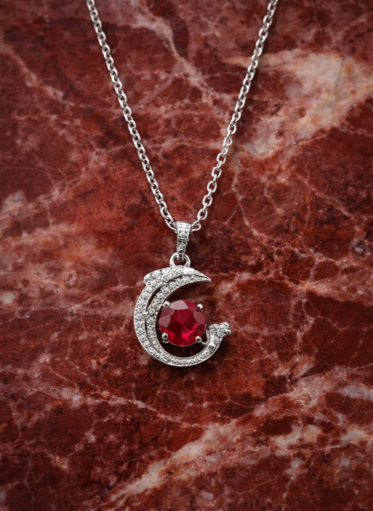 Silver necklace with a red gemstone pendant on a marbled background