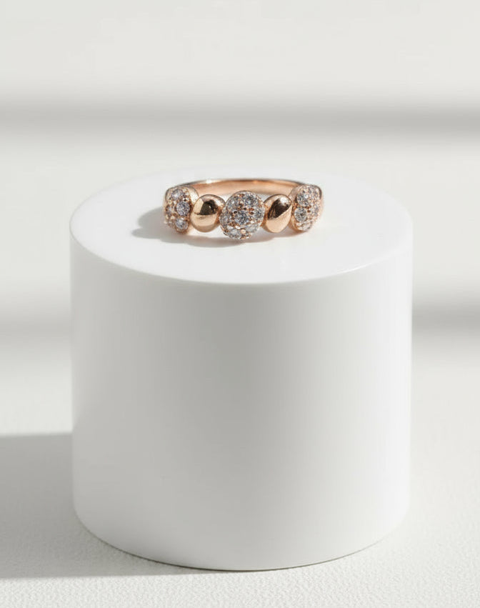 Rose gold ring with diamonds on a white pedestal