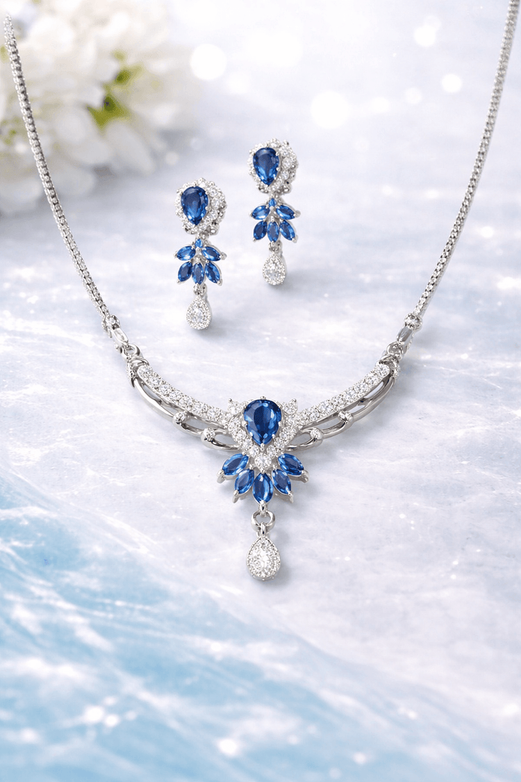 Jewelry set with necklace and earrings featuring blue gemstones on a light background