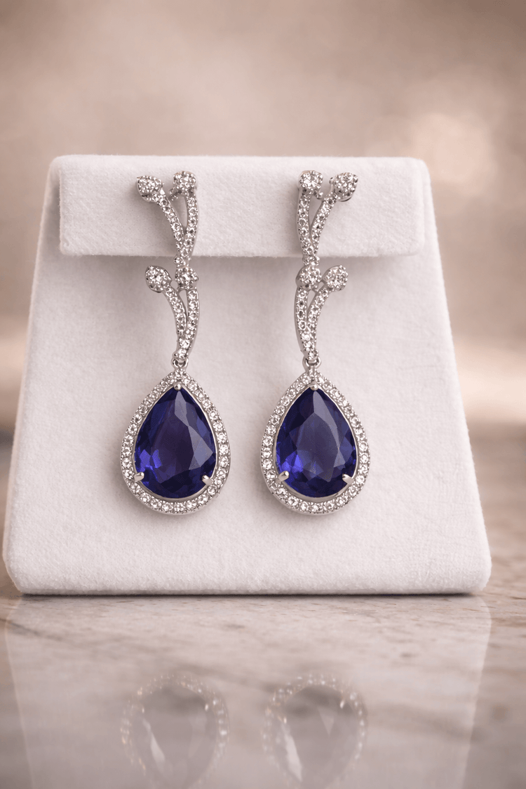 Pair of purple teardrop earrings on a white jewelry display