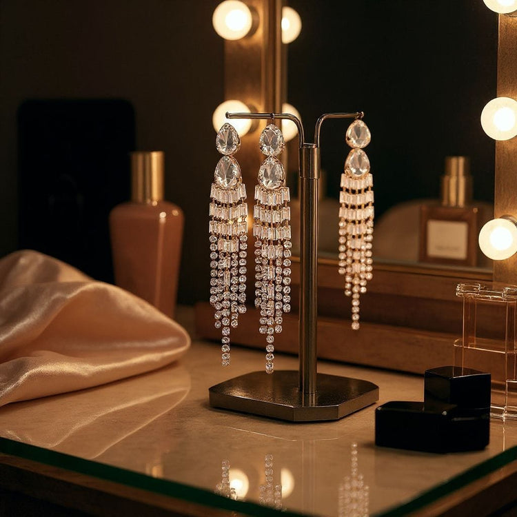 Pair of dangling earrings on a stand with a blurred vanity mirror background
