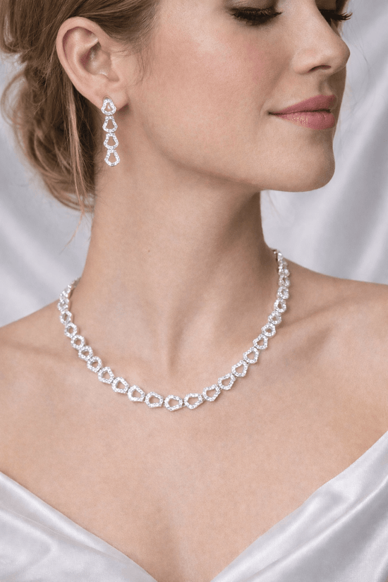 Woman wearing a silver necklace and earrings against a white background