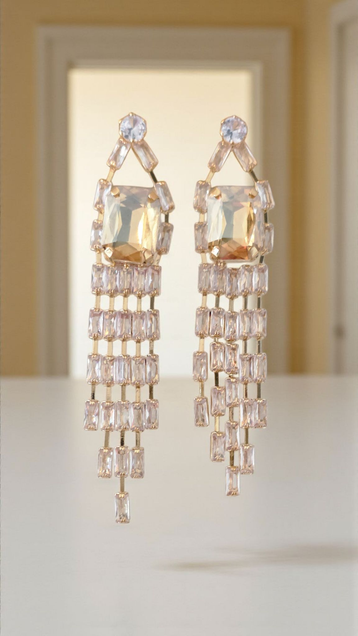 Pair of elegant chandelier earrings on a white surface with a blurred background
