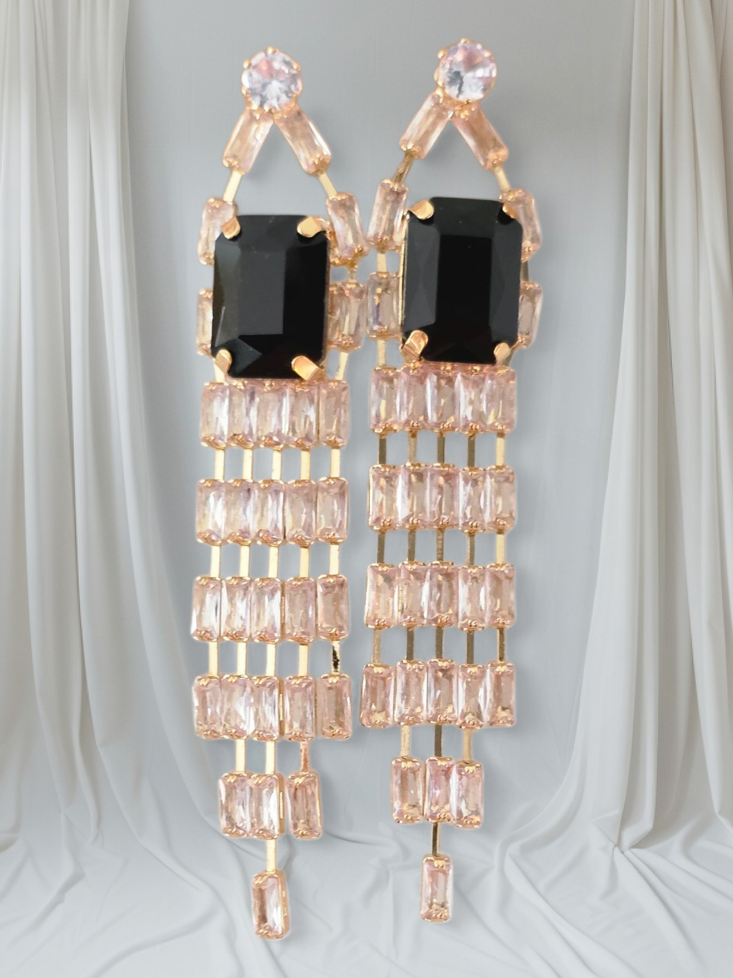 Elegant earrings with black and rose gold accents on a light gray background