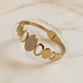 Gold bracelet with measurement details on a beige background