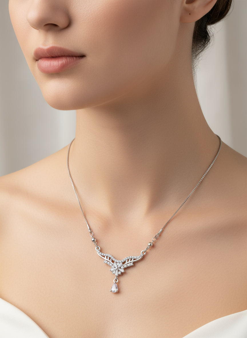Close-up of a woman wearing a silver necklace with a pendant against a neutral background