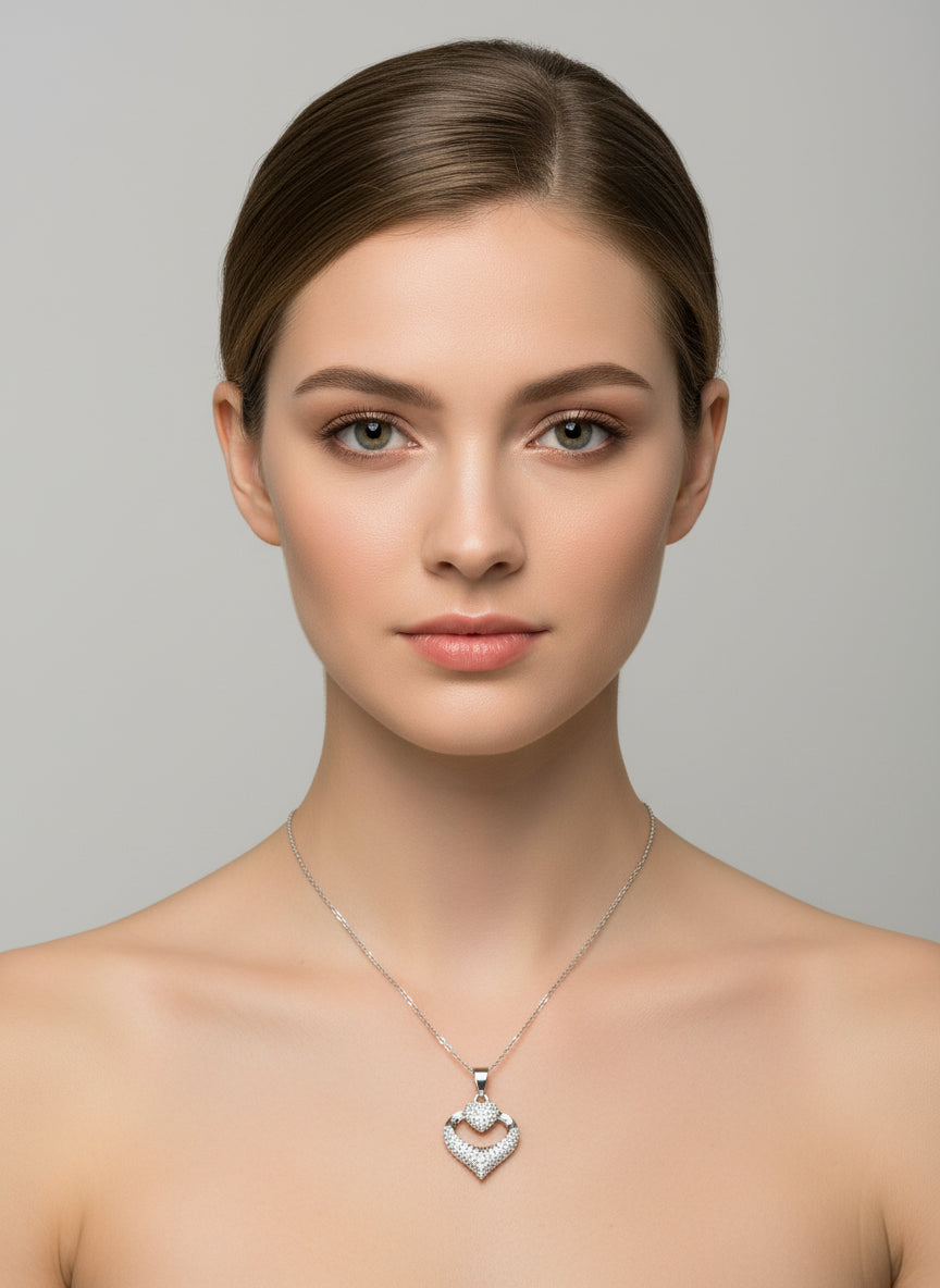 Woman wearing a silver necklace with a heart-shaped pendant against a gray background