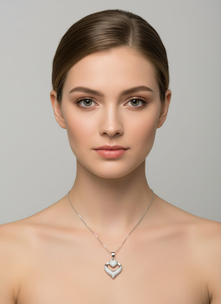 Woman wearing a silver necklace with a heart-shaped pendant against a gray background