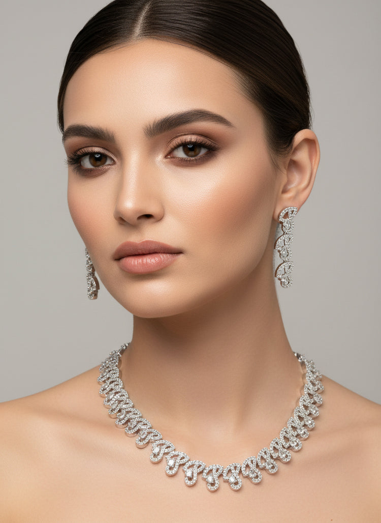 Woman wearing a silver necklace and earrings against a gray background