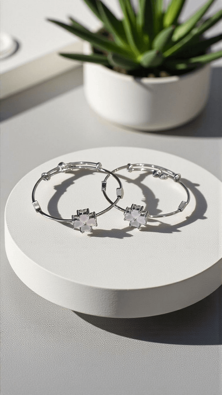 Silver hoop earrings with star-shaped stones on a white surface, with a potted plant in the background.