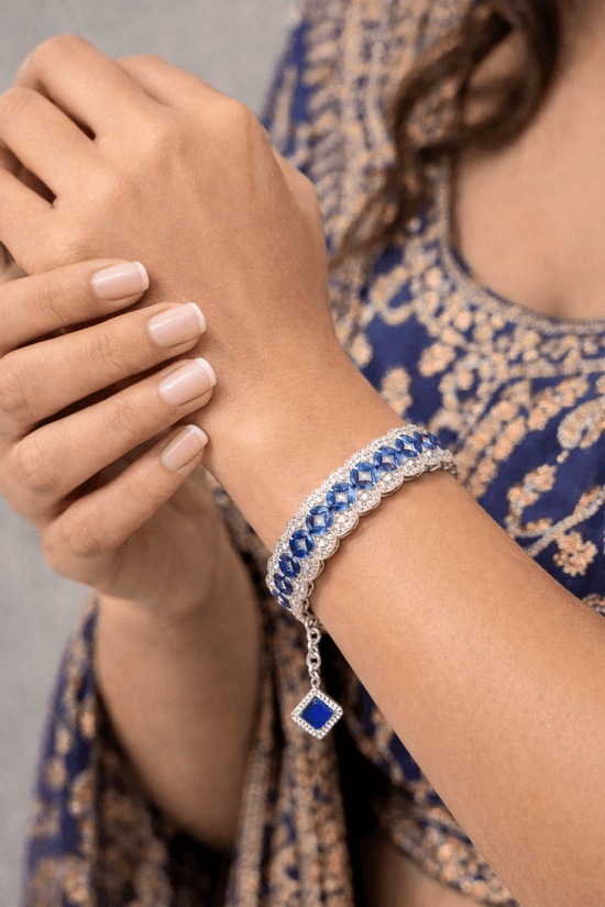 Close-up of a hand wearing a blue gemstone bracelet with a matching blue scarf.