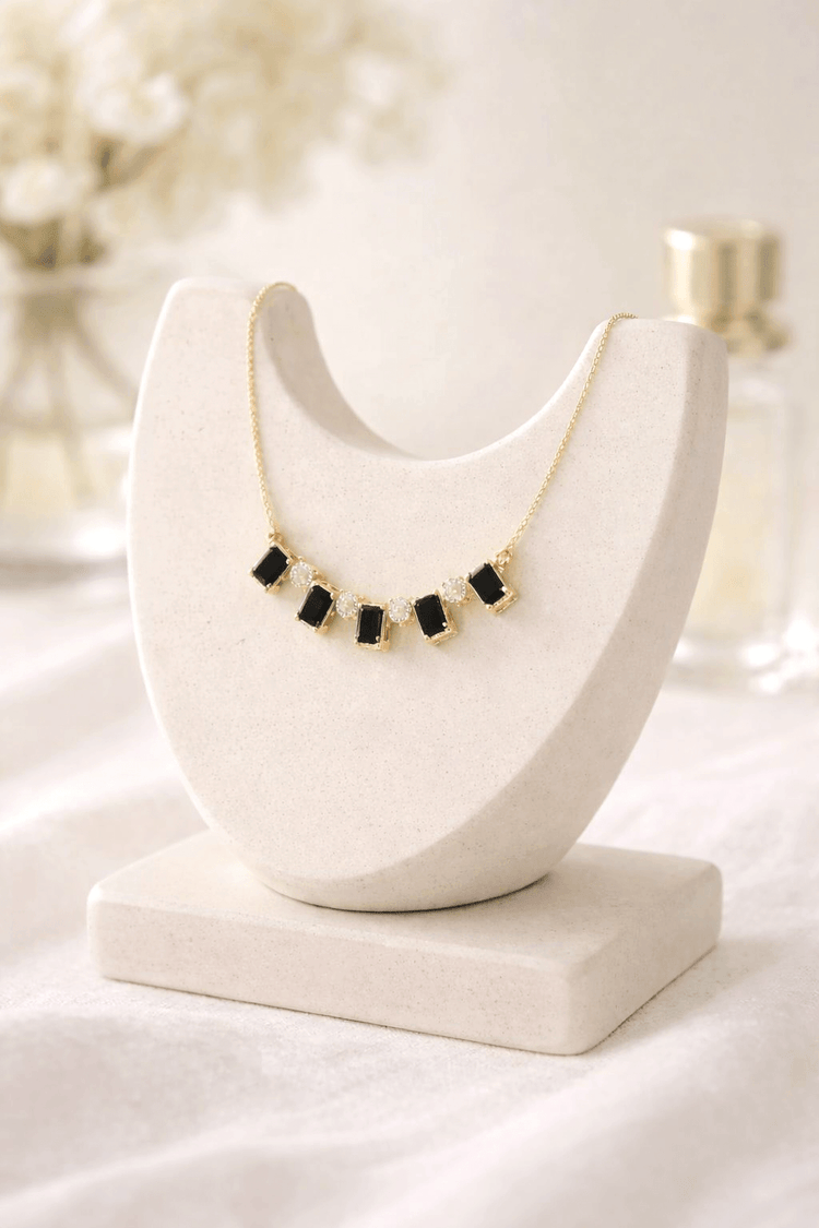 Necklace with black beads on a white marble stand against a blurred background