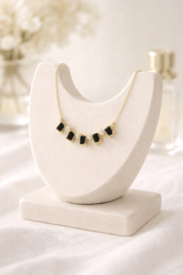 Necklace with black beads on a white marble stand against a blurred background