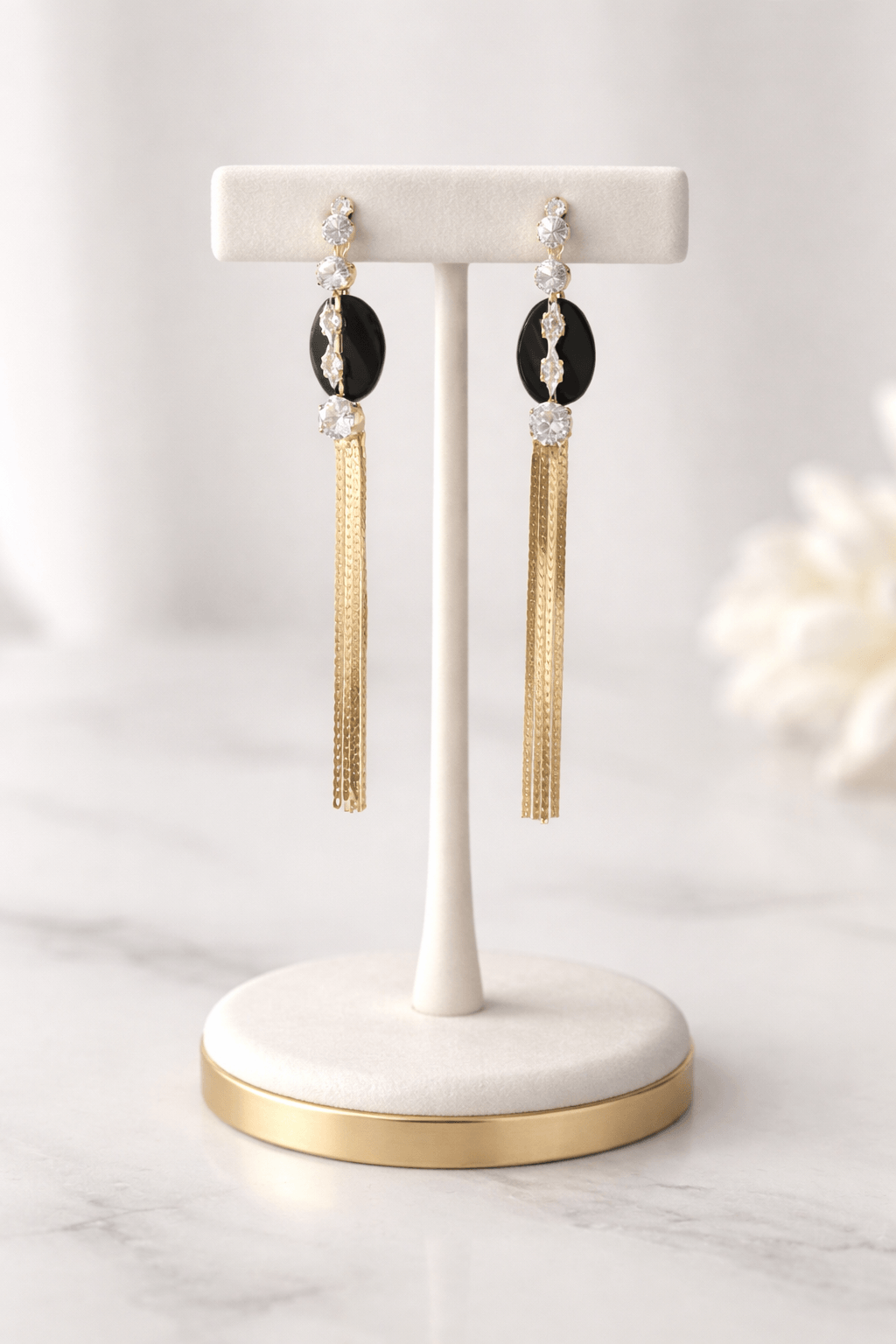 Gold tassel earrings with crystal and black stone details on display