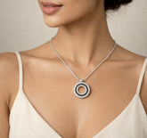 Necklace with a circular pendant worn by a model against a neutral background