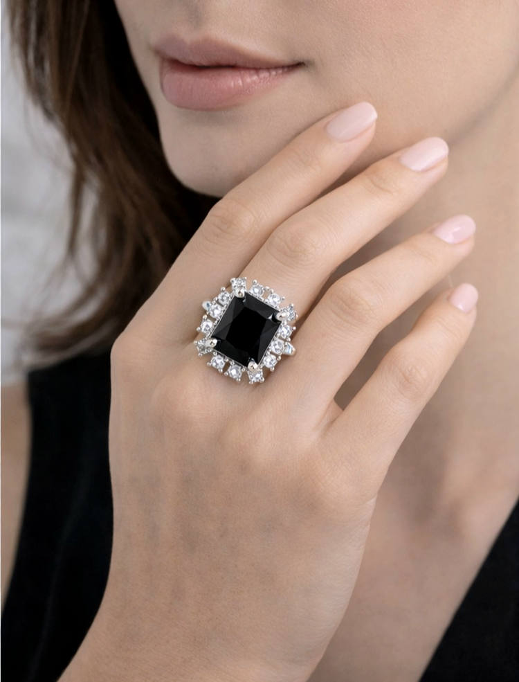 Close-up of a hand wearing a black gemstone ring with diamond accents.