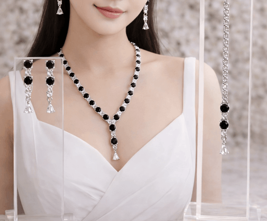 Woman wearing a black and white beaded necklace with matching earrings against a neutral background