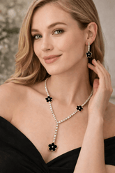 Woman wearing a necklace and earrings with floral designs, against a neutral background