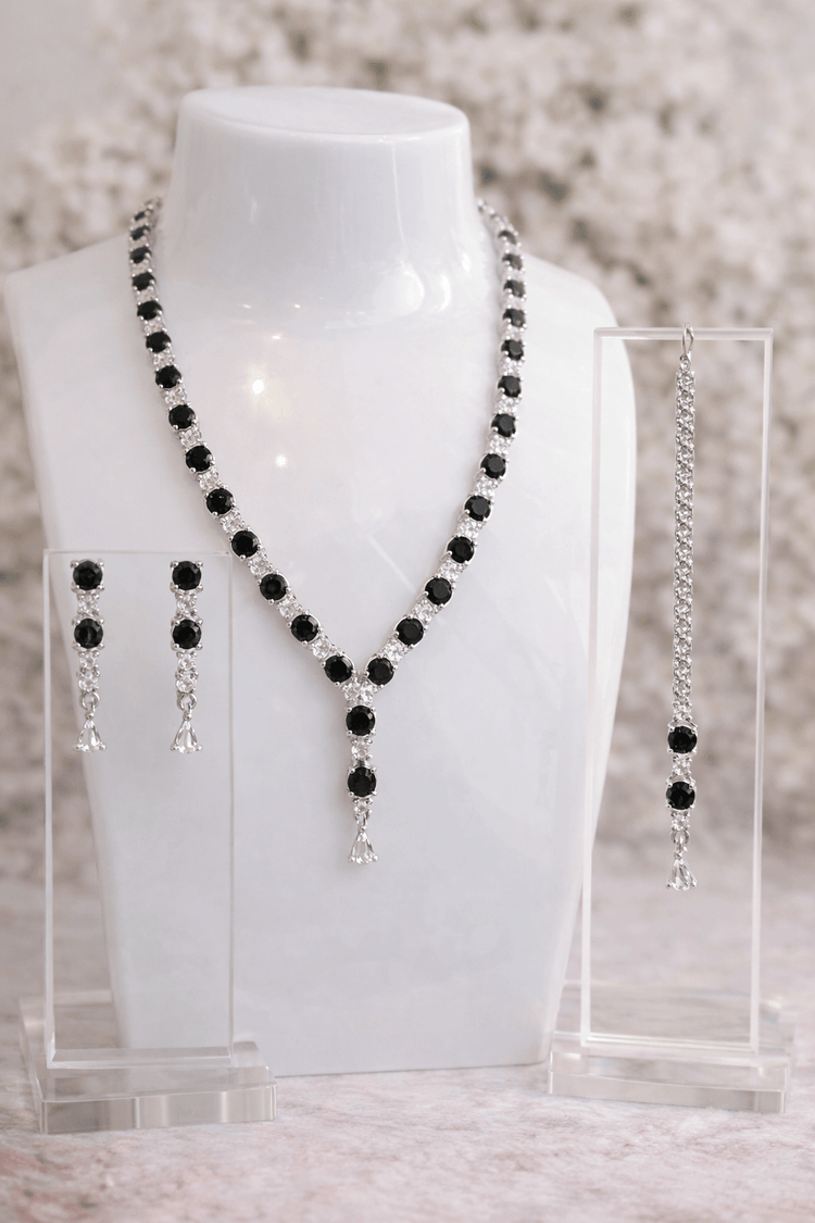 Black beaded necklace and earrings on a mannequin bust with a blurred background