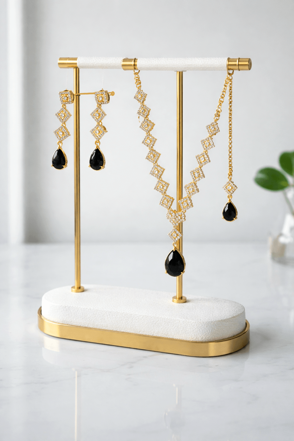 Gold and black earrings on a white and gold stand against a light background