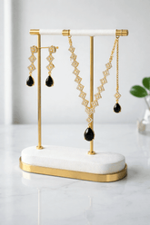 Gold and black earrings on a white and gold stand against a light background
