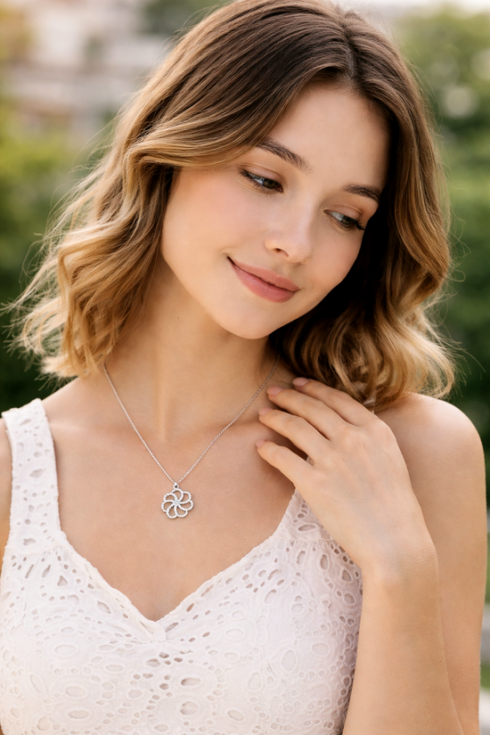 Woman wearing a silver necklace with a floral pendant outdoors