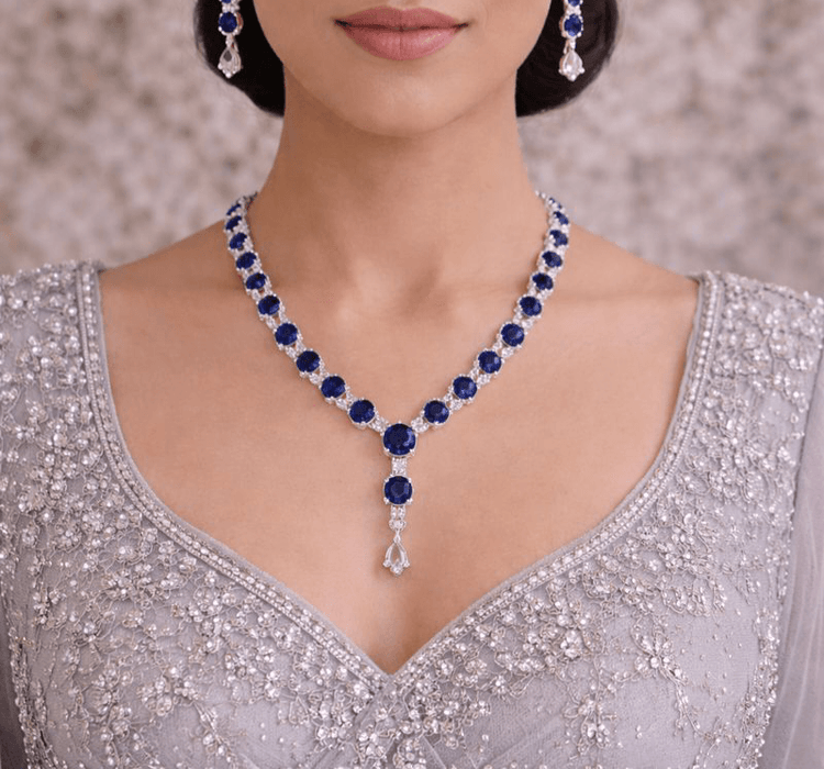 Woman wearing a blue gemstone necklace and earrings on a neutral background