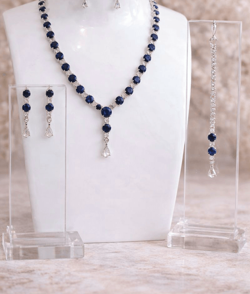 Jewelry set with necklace, earrings, and bracelet on a white stand.