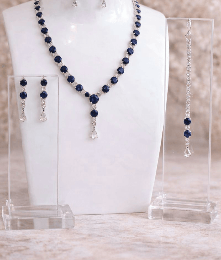 Jewelry set with necklace, earrings, and bracelet on a white stand.