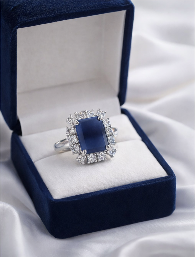 Blue gemstone ring in a blue velvet box on a white fabric background