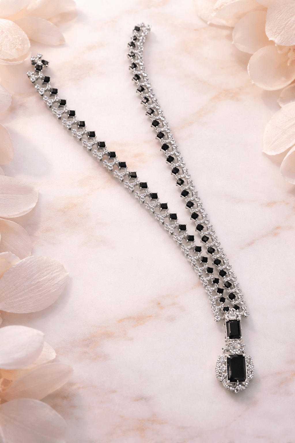 Silver bracelet with black stones on a light pink floral background