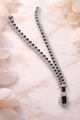 Silver bracelet with black stones on a light pink floral background