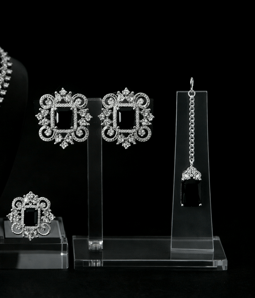 Set of silver earrings on clear stands against a black background