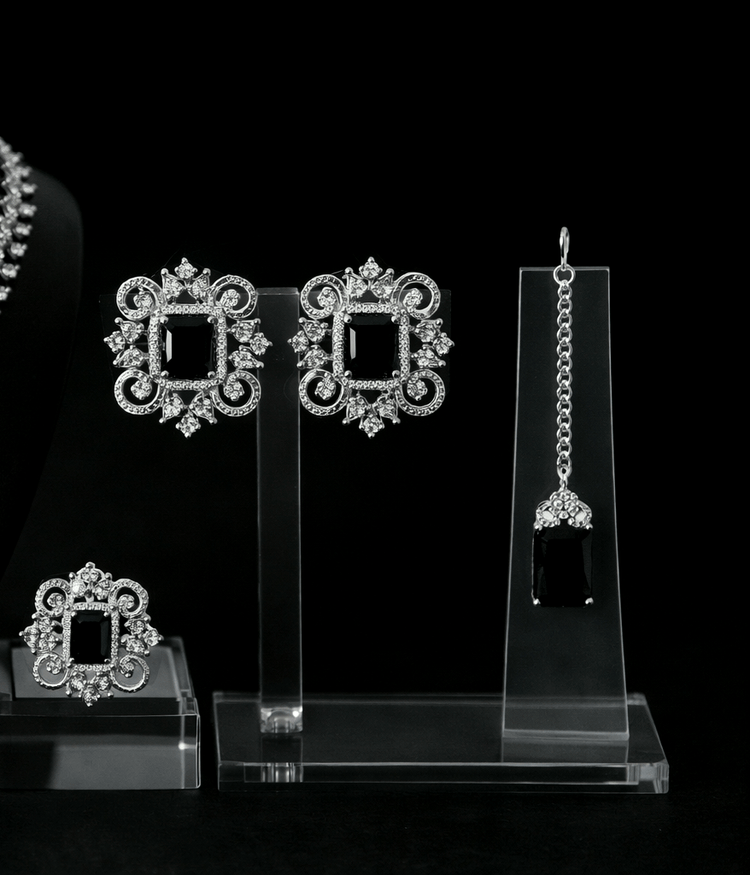 Set of silver earrings on clear stands against a black background