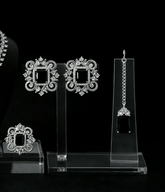 Set of silver earrings on clear stands against a black background