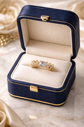 Gold ring with a large diamond in a blue jewelry box on a marble surface