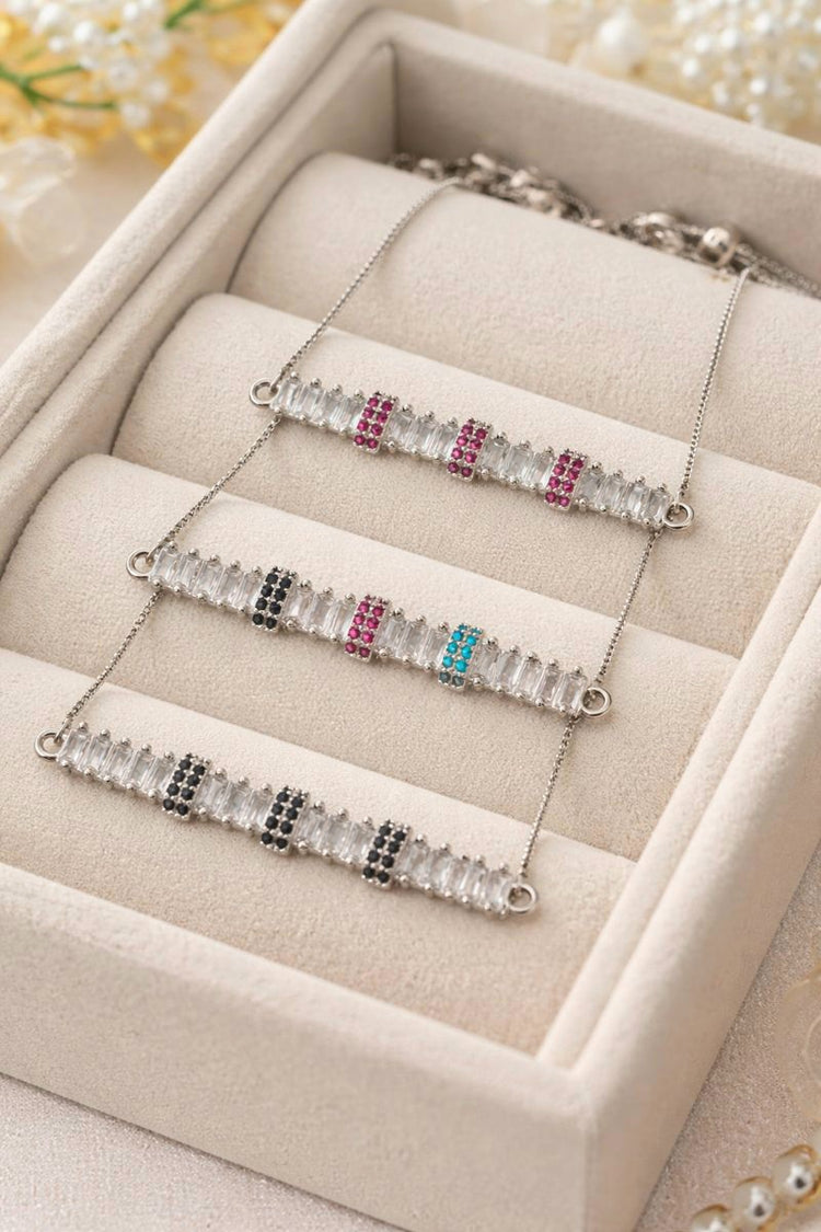 Three silver bracelets with gemstones on a beige jewelry box