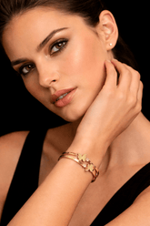 Woman wearing a gold bracelet with a black background
