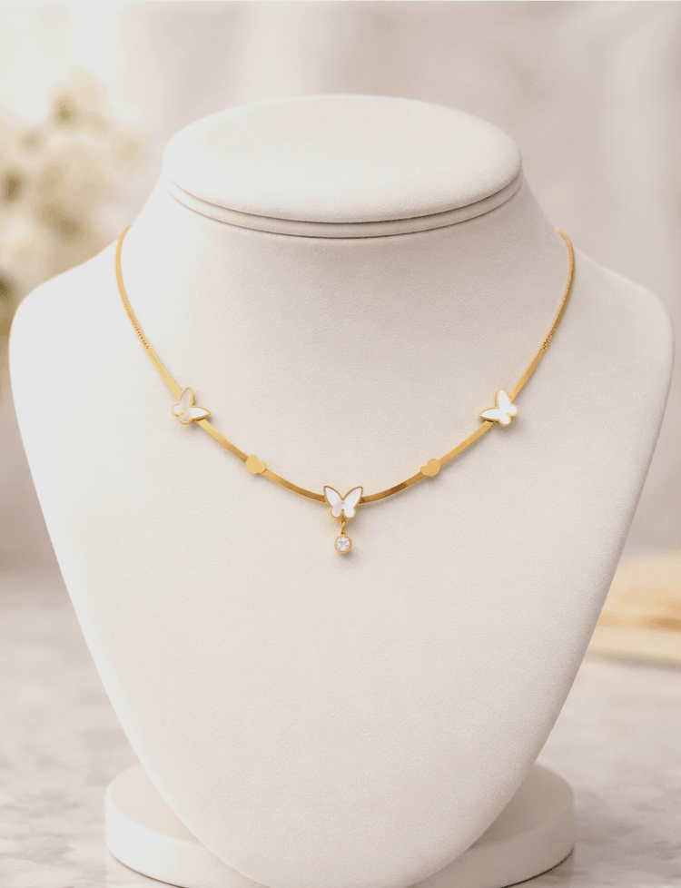 Gold necklace with butterfly pendants on a mannequin bust against a blurred background