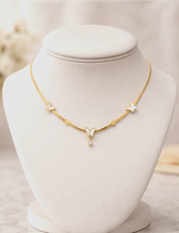 Gold necklace with butterfly pendants on a mannequin bust against a blurred background