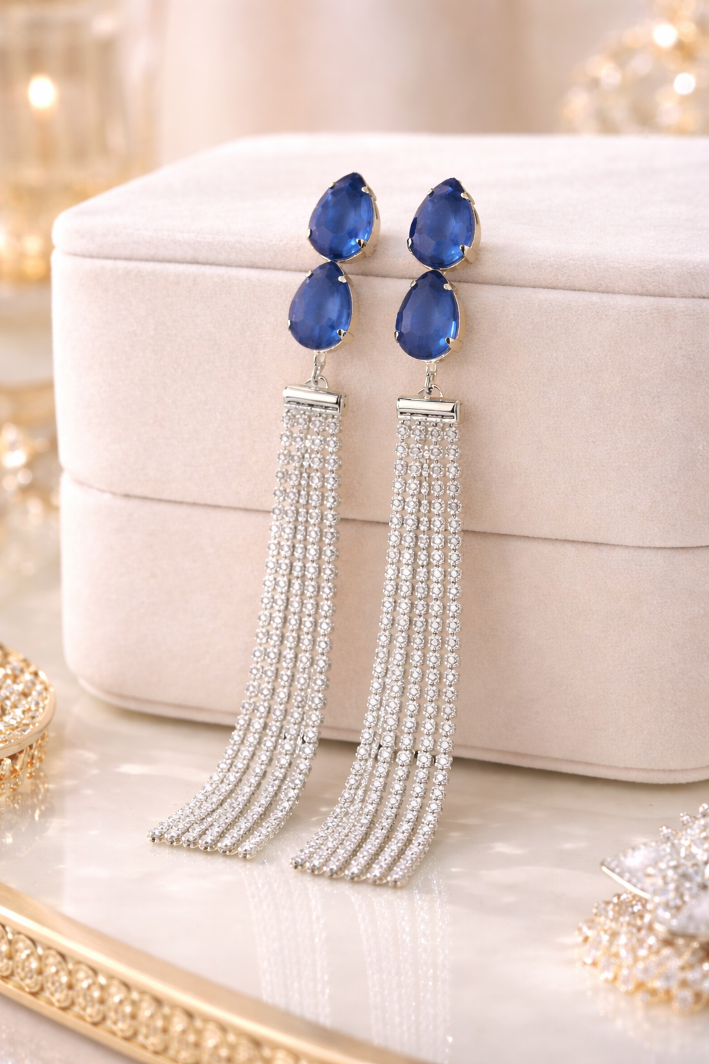Pair of blue teardrop earrings with silver tassels on a decorative surface.