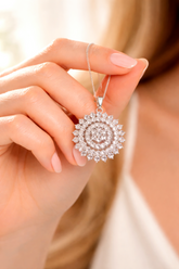 Close-up of a hand holding a diamond necklace with a spiral design.