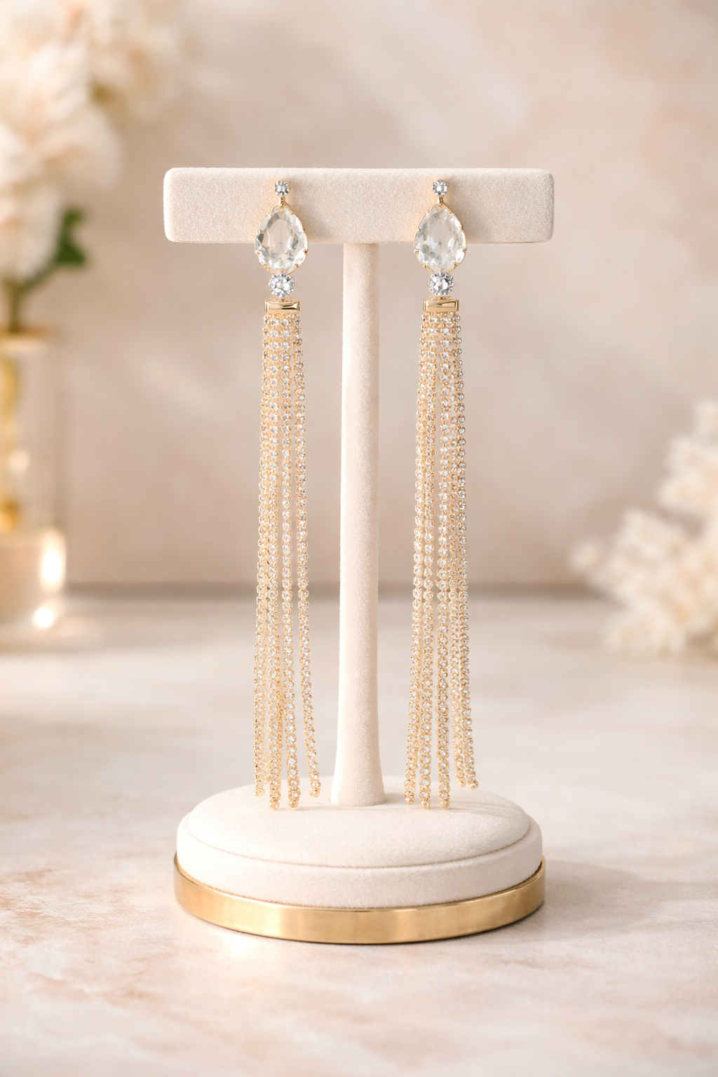 Pair of tassel earrings on a decorative stand with a soft, blurred background