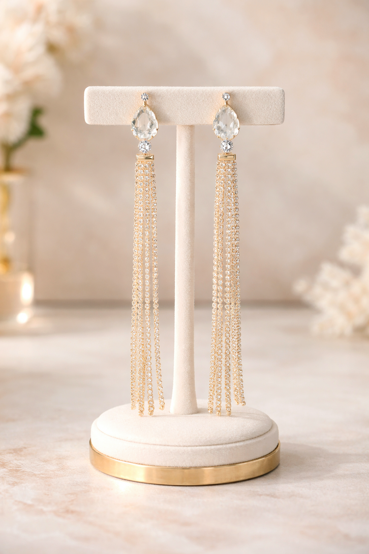 Pair of tassel earrings on a decorative stand with a soft, blurred background