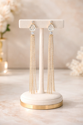 Pair of tassel earrings on a decorative stand with a soft, blurred background