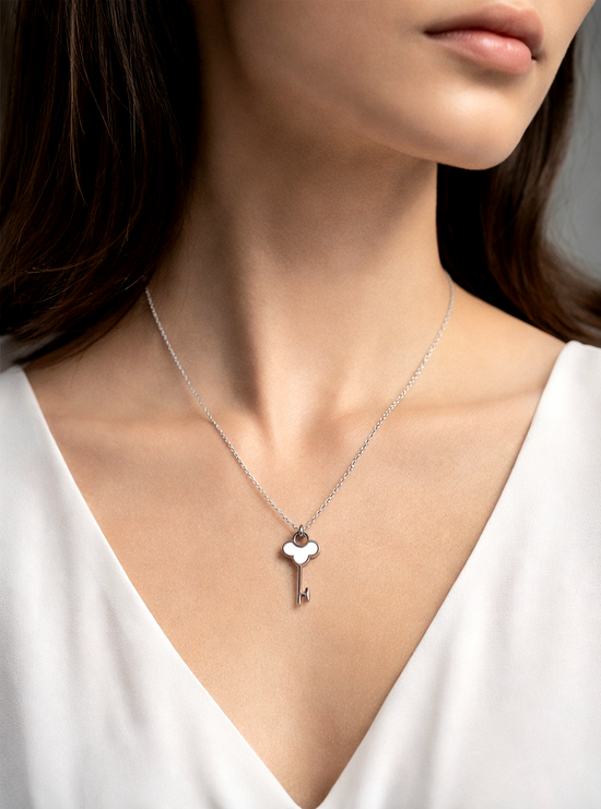 Necklace with a heart-shaped key pendant worn by a person in a white top.